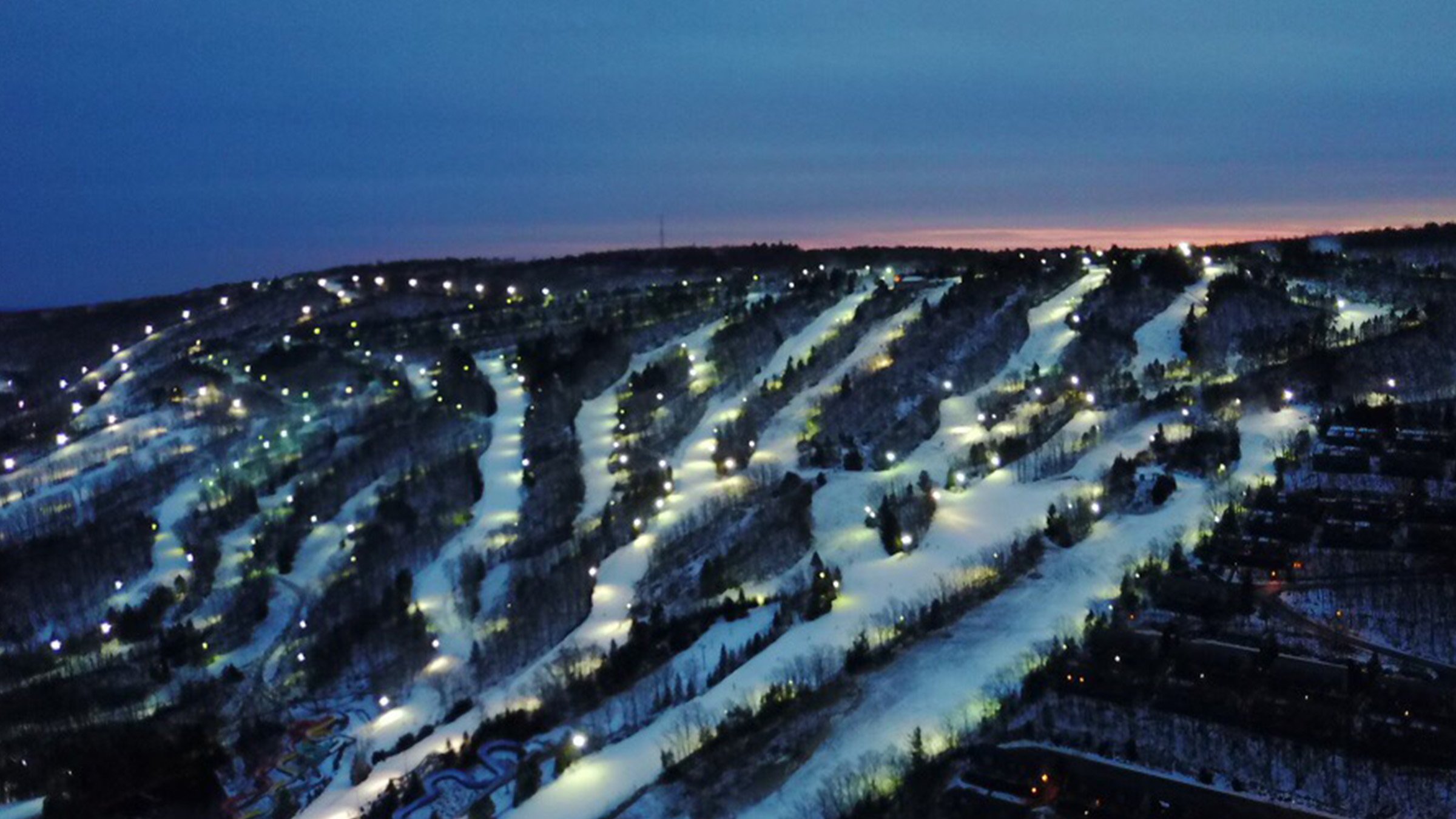 Illuminated ski slopes photographed by drone at dusk
