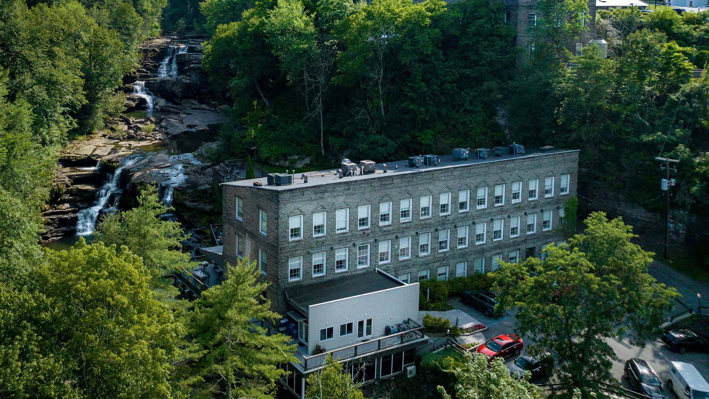 Aerial view of a historic stone building beside a cascading waterfall